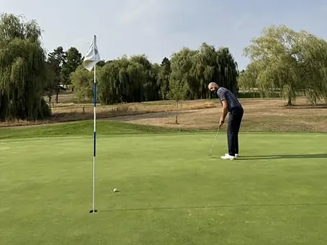 Green et drapeau, Alexis Weizman au putting en arrière-plan